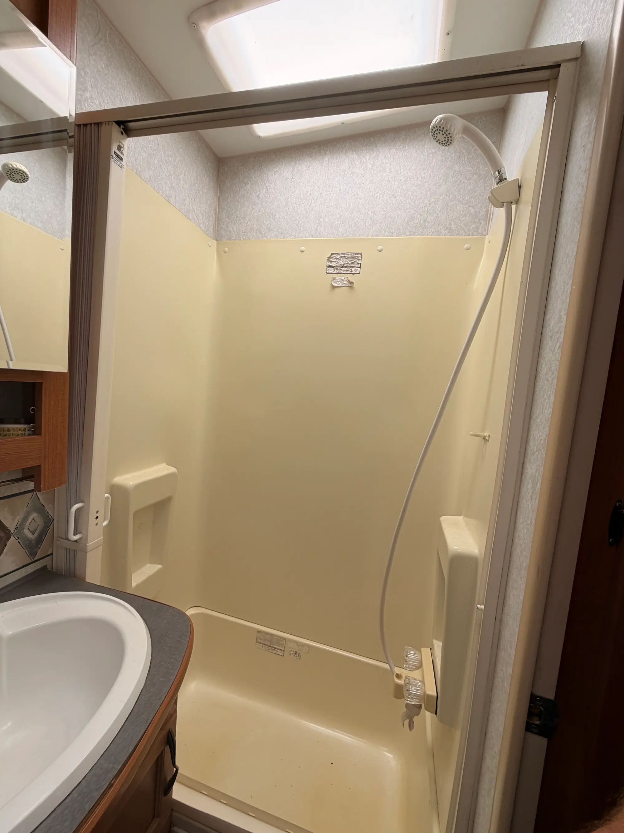 Enclosed shower stall with a handheld sprayer inside the fifth wheel bathroom