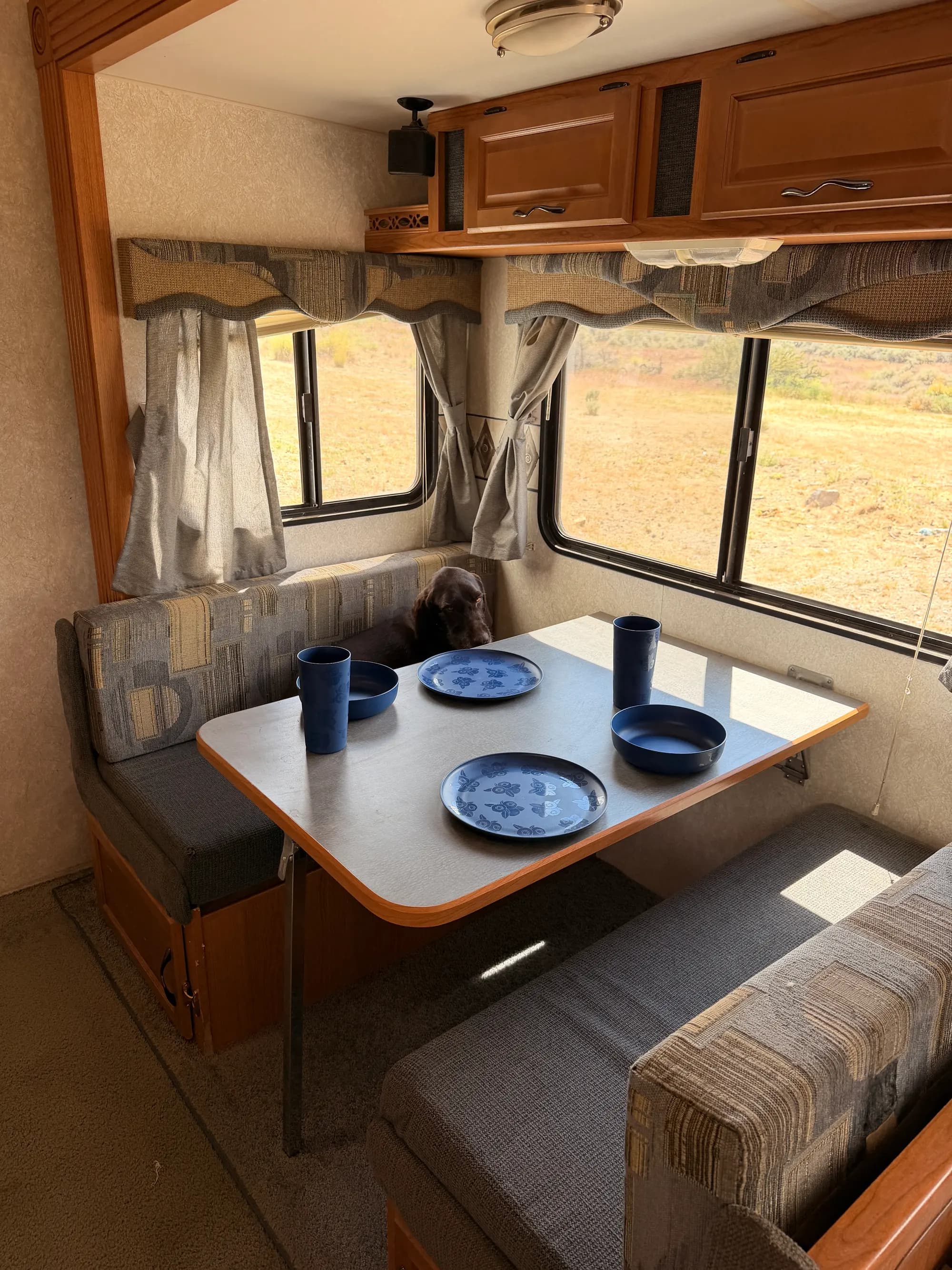 Dinette booth set with plates and cups, desert visible through the window